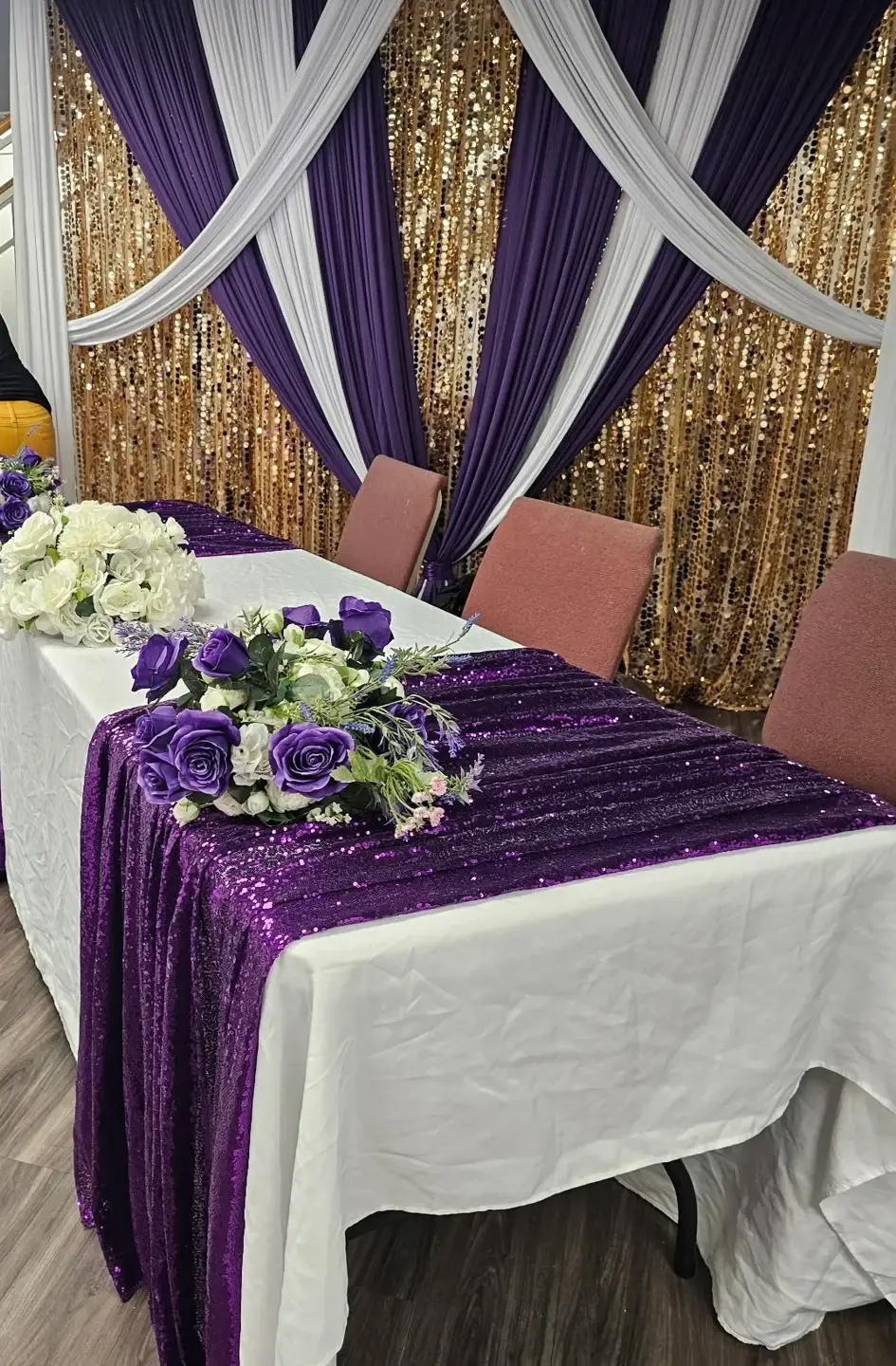 Purple and gold celebration table with draped fabric backdrop
